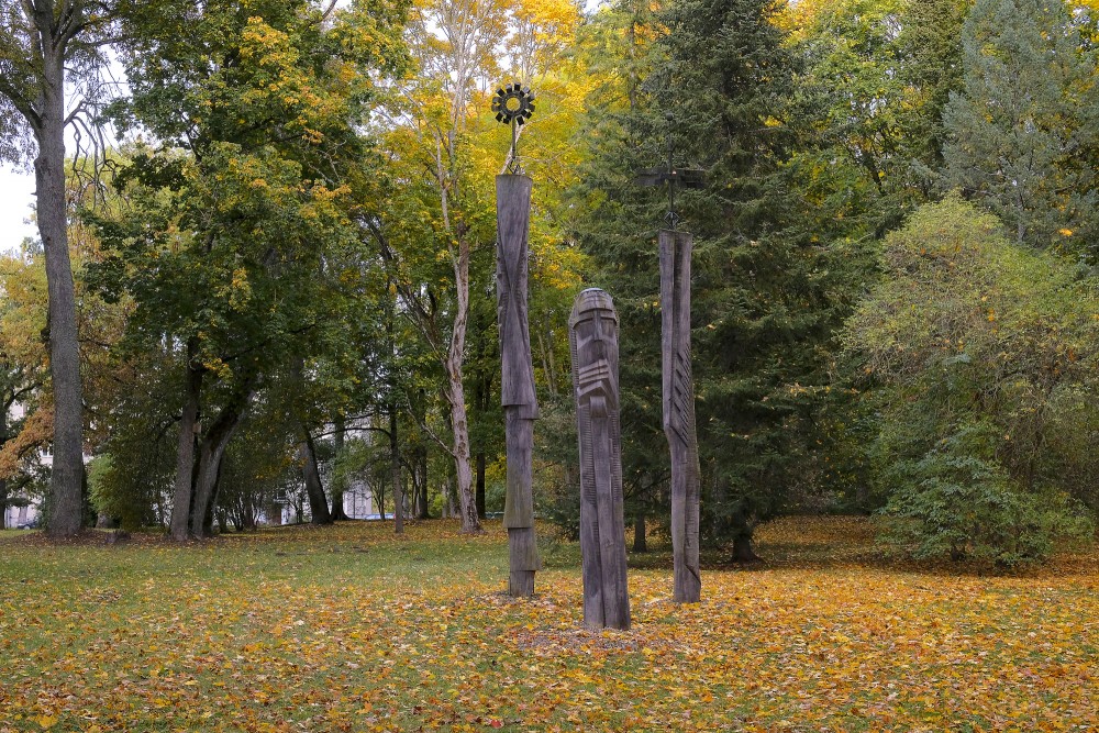 Tall Wooden Sculptures in Park Surrounded by Golden Autumn Trees