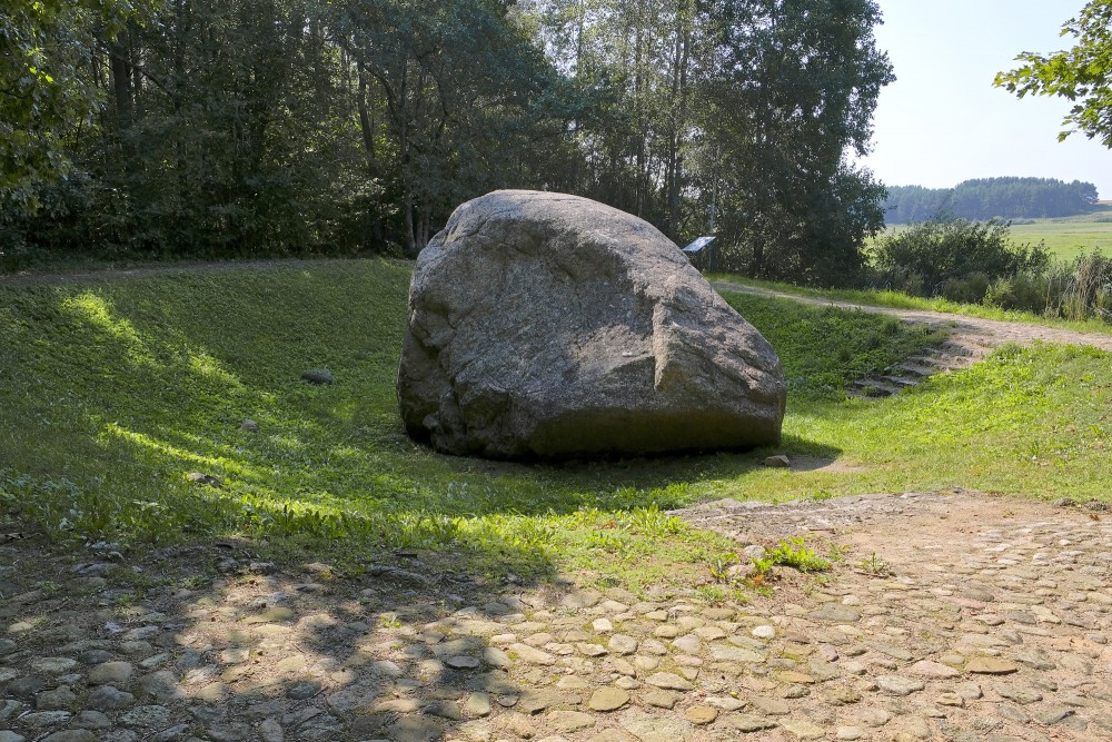 Šilalės Kūlis boulder in a green hollow near a cobblestone path and forest edge