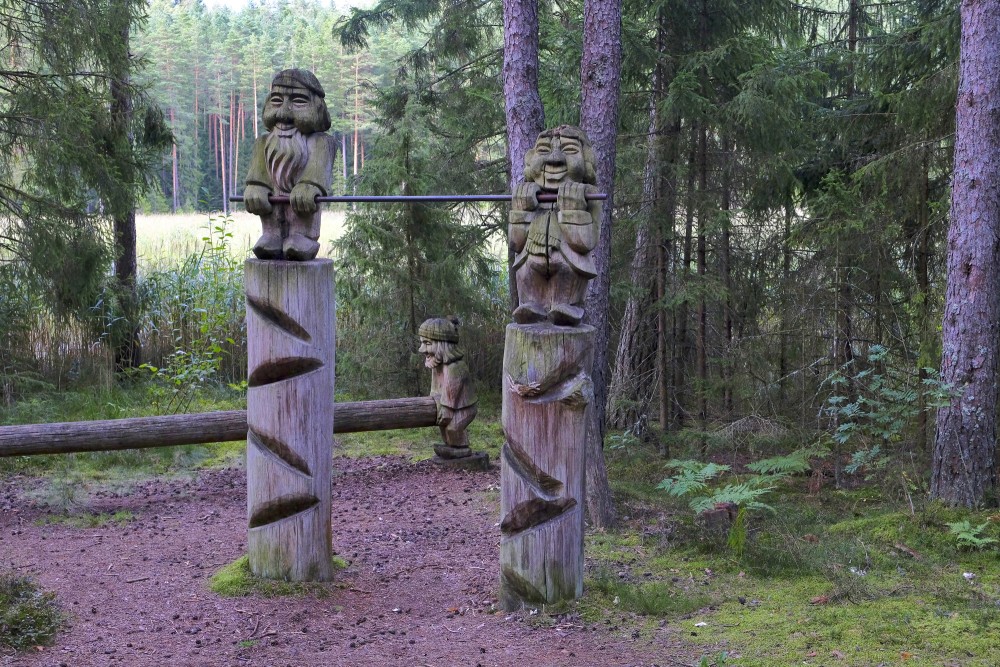 Wooden sculptures by a forest obstacle with a log between posts