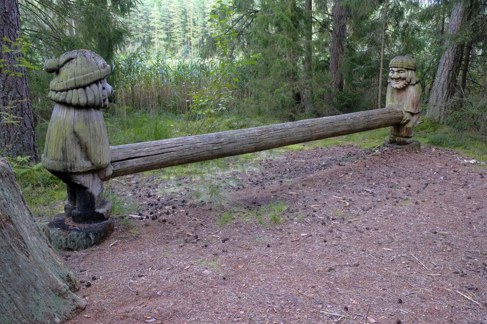 Wooden sculptures with a long log in a forest clearing near reeds