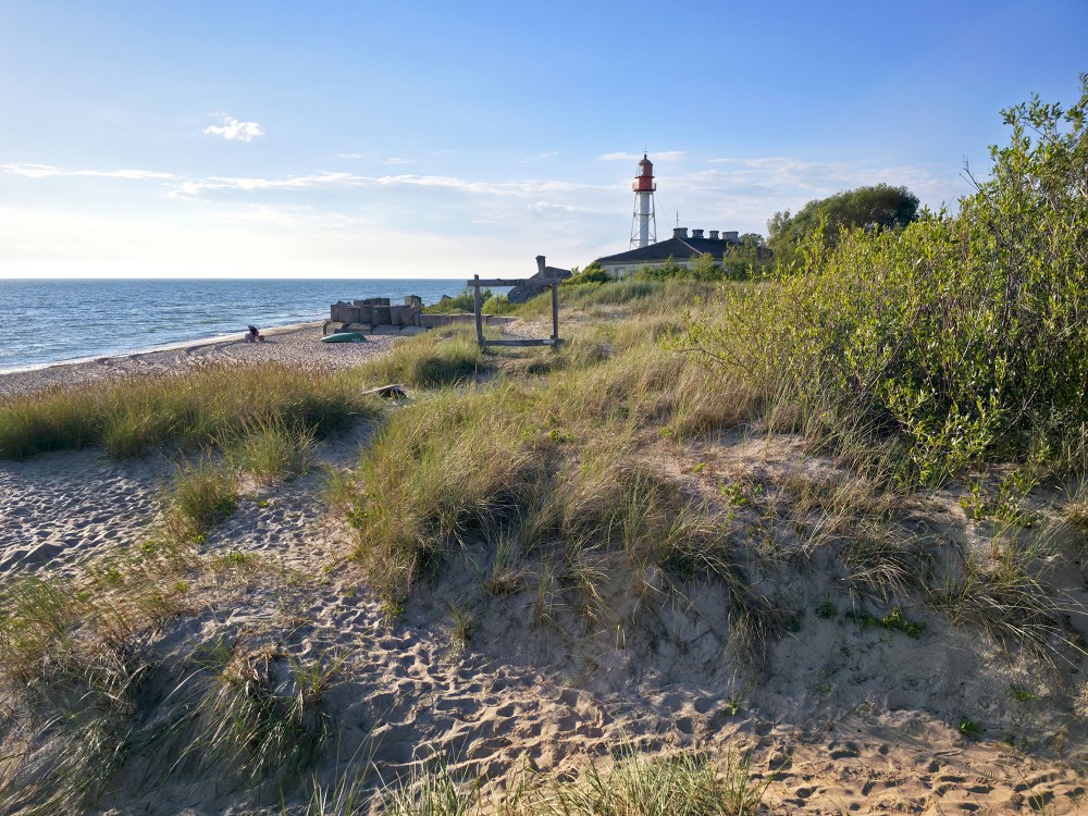 Sunny coastal landscape with Pape lighthouse, sand dunes and the Baltic Sea