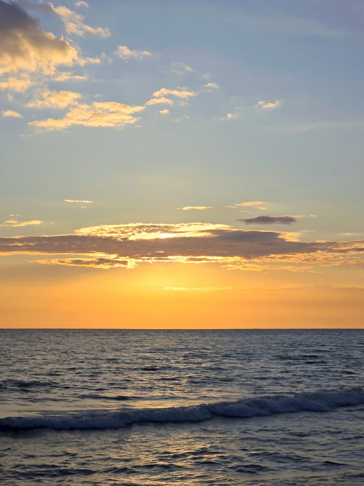 Golden sunset over a calm sea with clouds and gentle waves