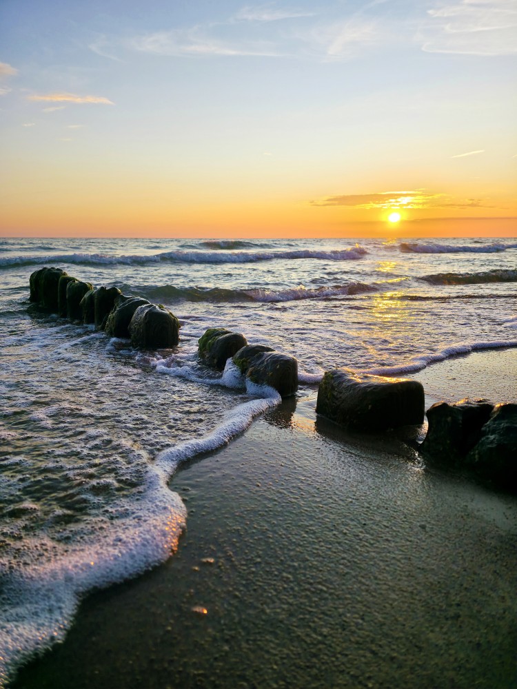 Waves crashing on submerged wooden pier during golden sunset