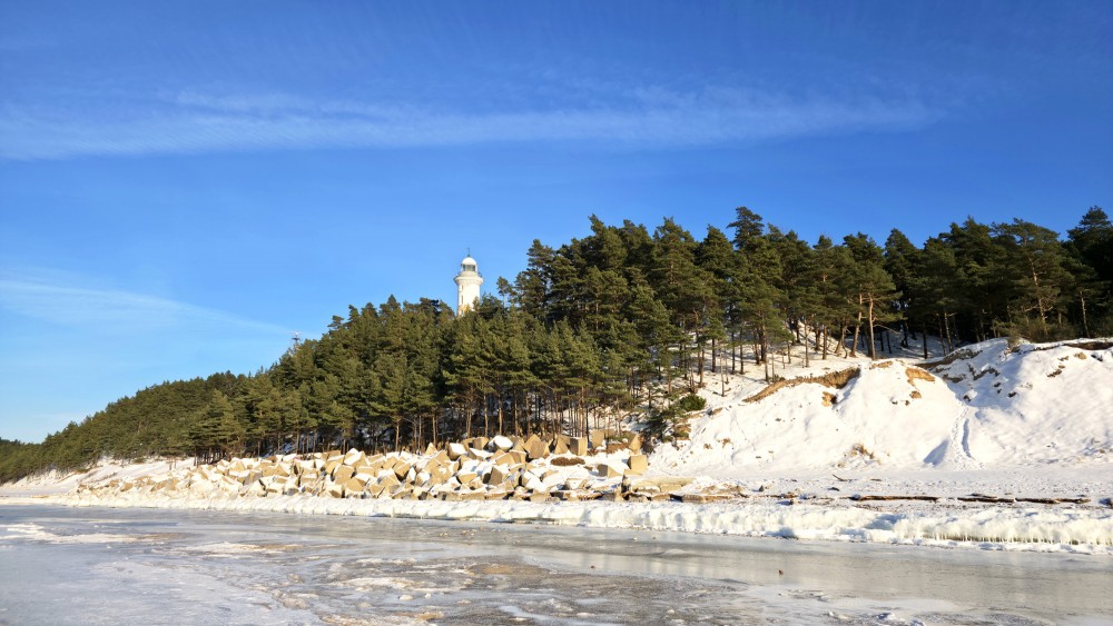 Užava lighthouse against a snowy dune in winter