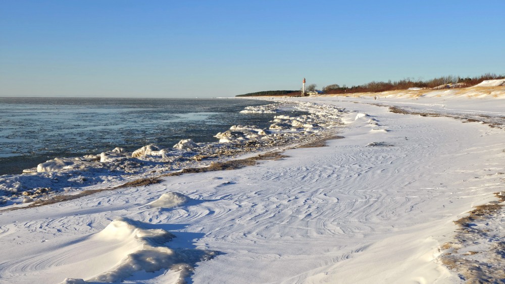 Winter landscape with Pape Lighthouse and frozen Baltic Sea coast