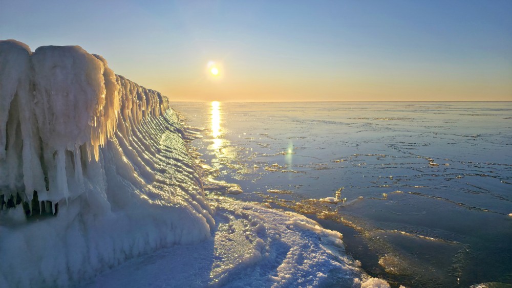 Sun reflection in the frozen sea by the Pape wooden piles