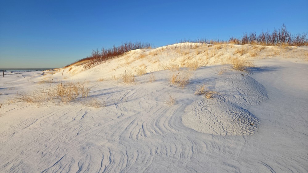 Winter sunset light on snow-covered dunes at Pape beach