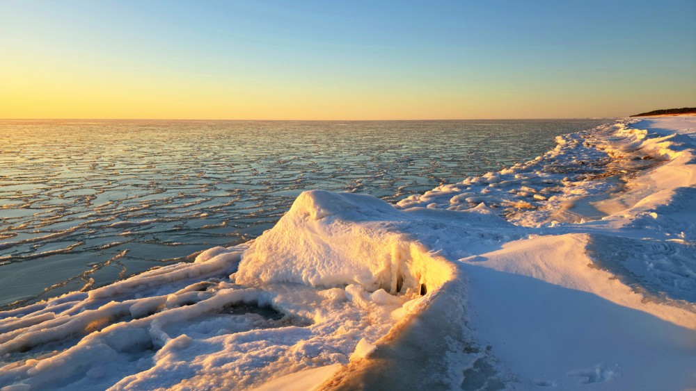 Sunset light on ice ridges and a frozen sea at Pape beach