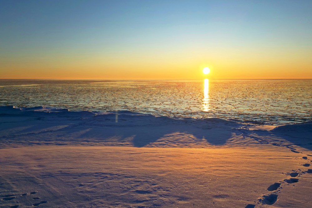 Sunset over a frozen sea and snowy coastline