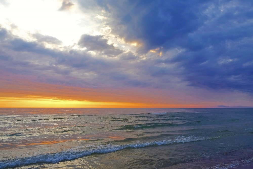 Saulriets Baltijas jūrā, mākoņainas debesi