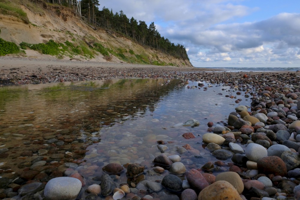 Rocky shoreline beneath coastal cliffs with calm reflective water