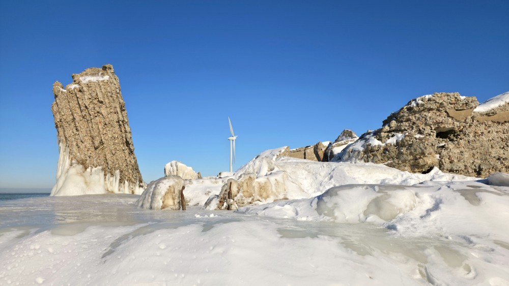 Vertical concrete ruins and a wind turbine in a winter landscape