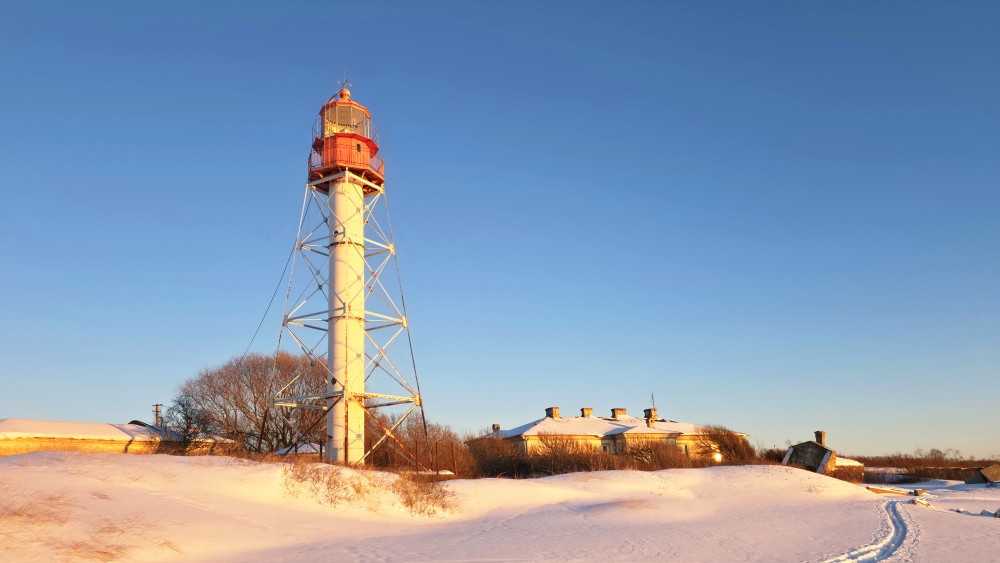 Pape lighthouse in winter sunlight and snow-covered dunes