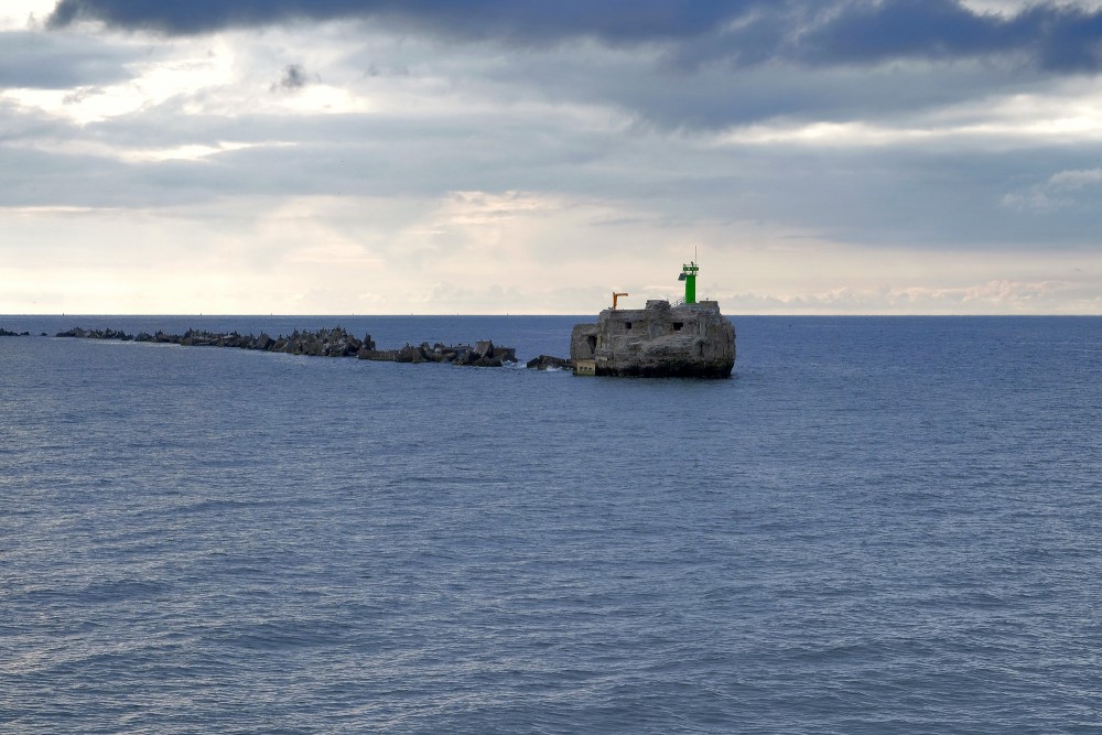Northern breakwater of Liepaja harbor with lighthouse on calm sea