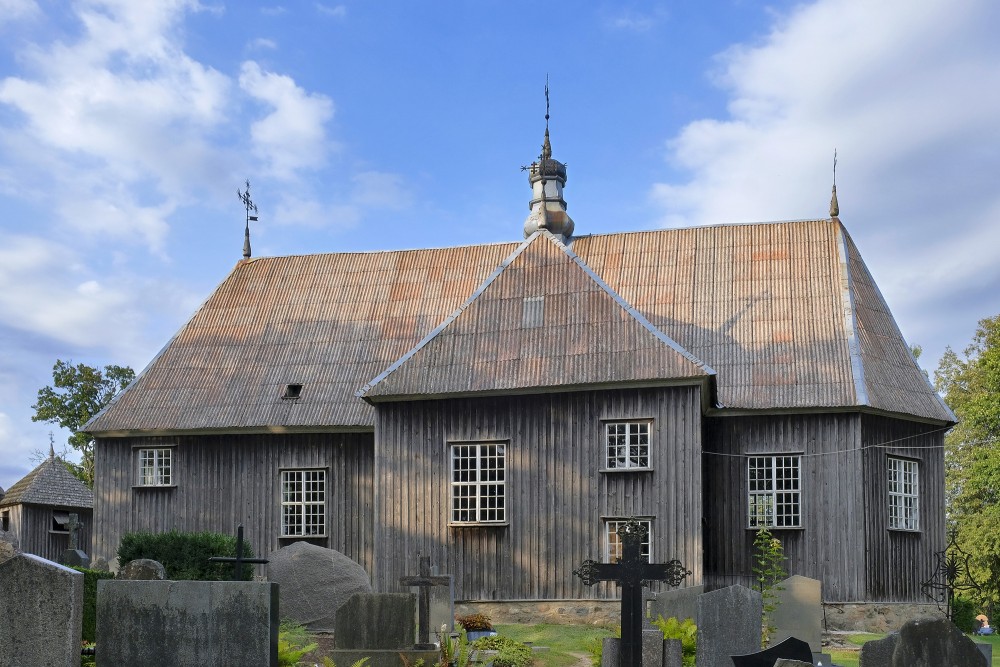 Side view of Beržoras St Bishop Stanislaus Church with cemetery monuments