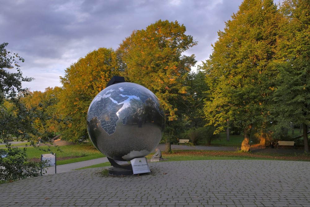 Globe art installation in Liepaja Seaside Park surrounded by autumn trees